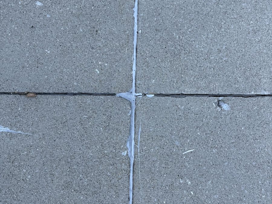 Old caulk sealant cracked and peeling out of a driveway joint intersection