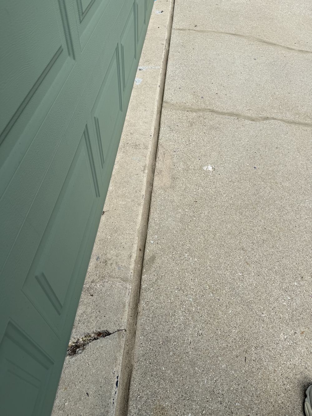Sealed joint along a garage apron running clean against the foundation